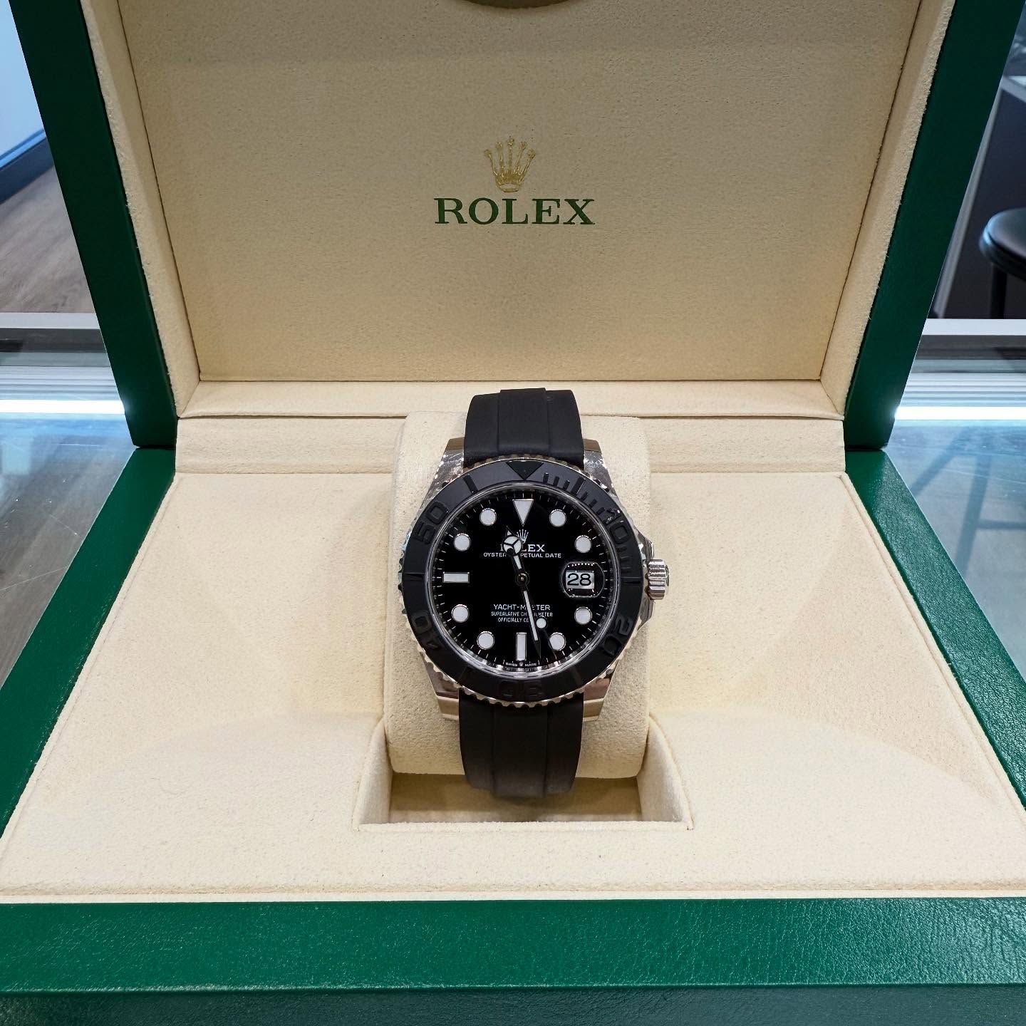 Rolex watch in an open green presentation box with cream interior.