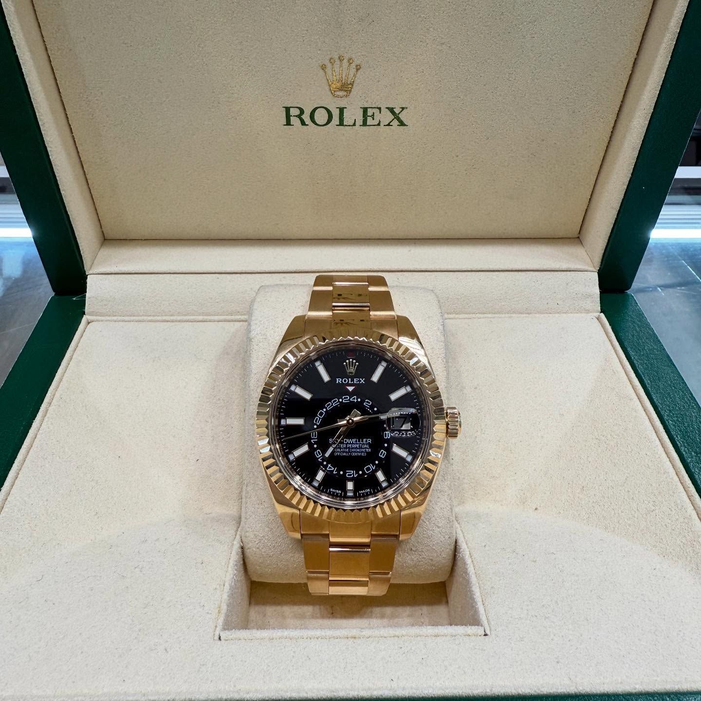 Gold Rolex watch with black dial in an open presentation box