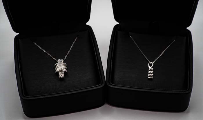 Two silver necklaces displayed in black velvet jewelry boxes