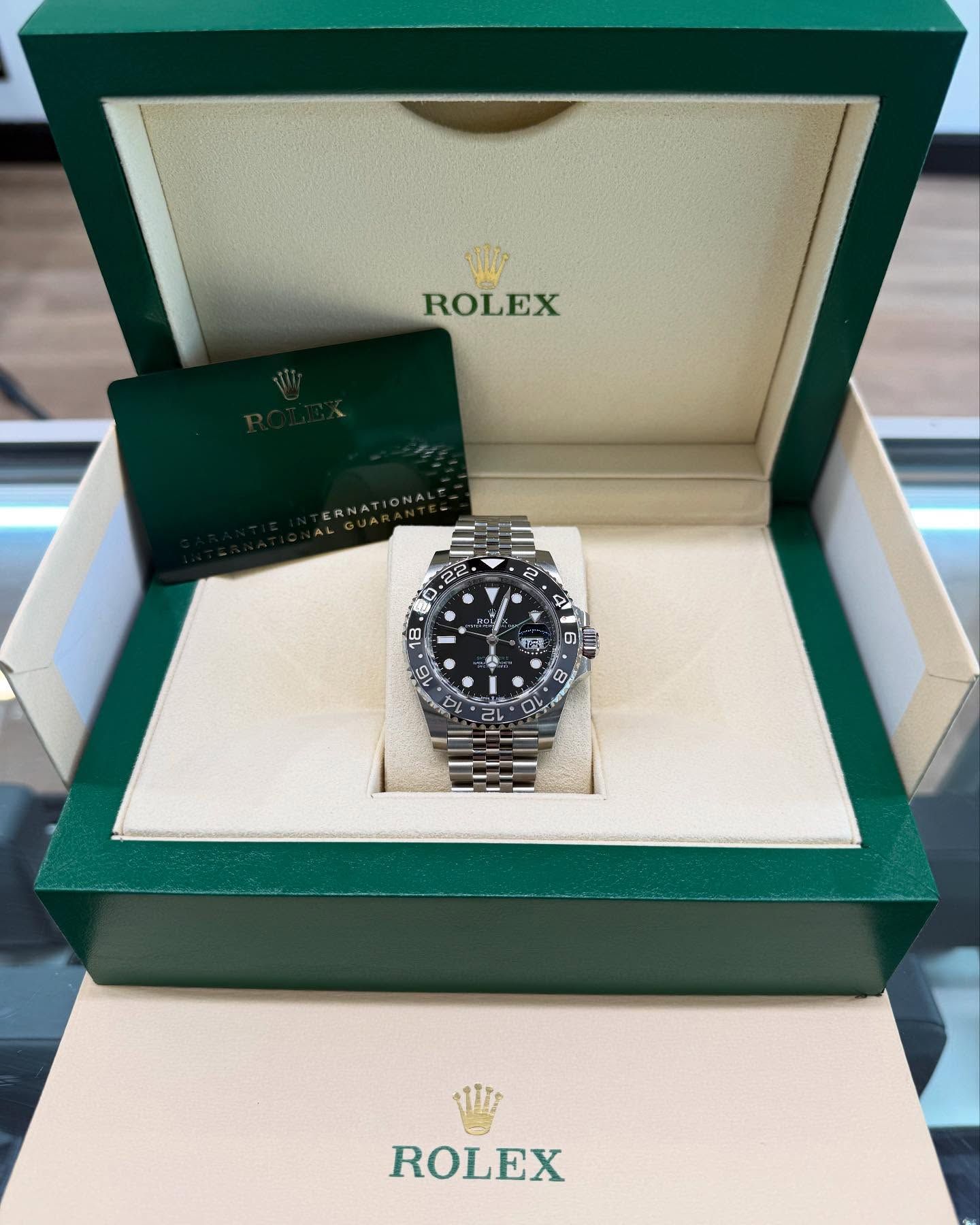 Rolex watch in open green presentation box with warranty card inside