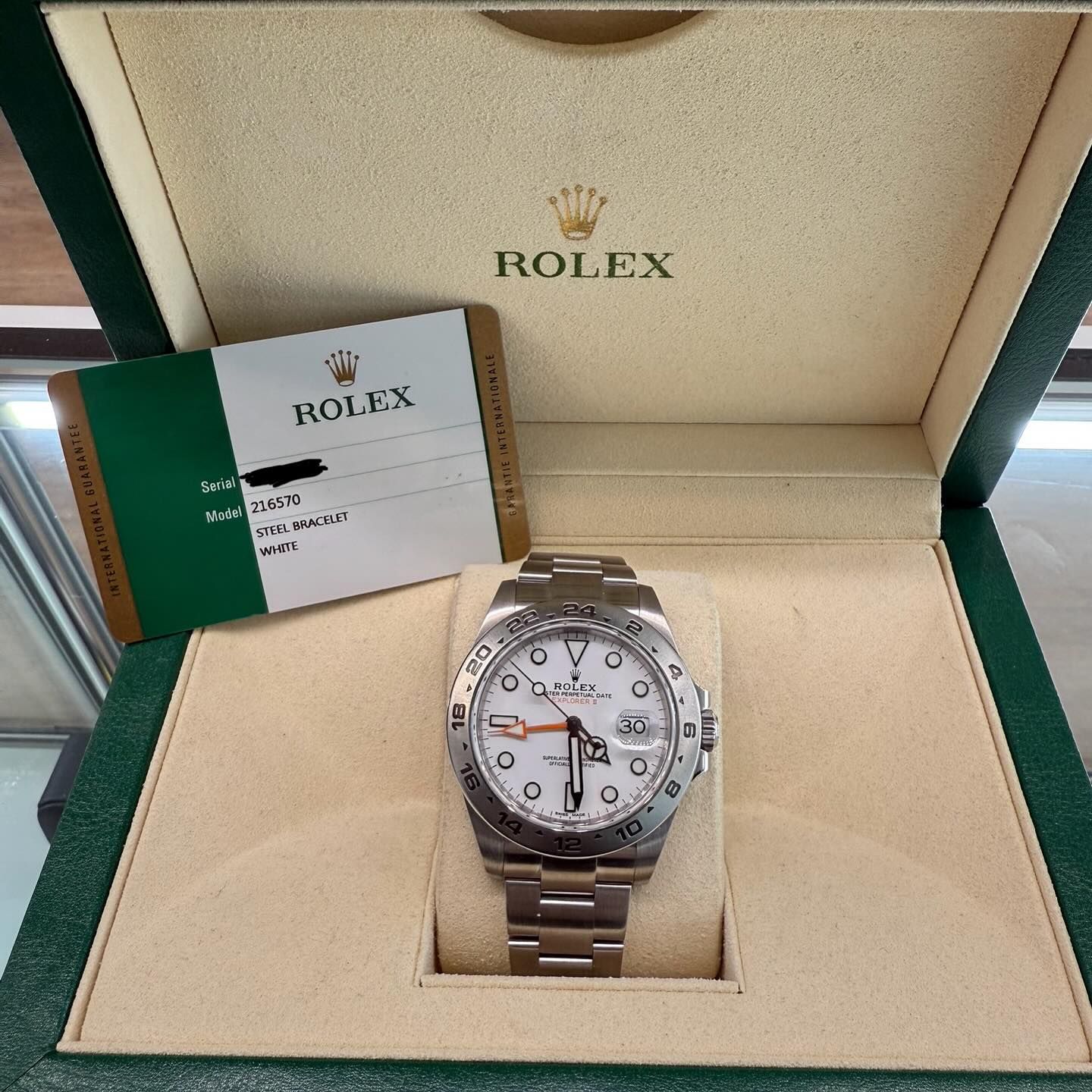 Rolex wristwatch in an open beige presentation box with warranty card