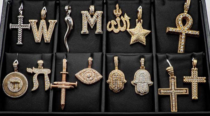 Assorted gold and silver religious pendants displayed in rows on a black background