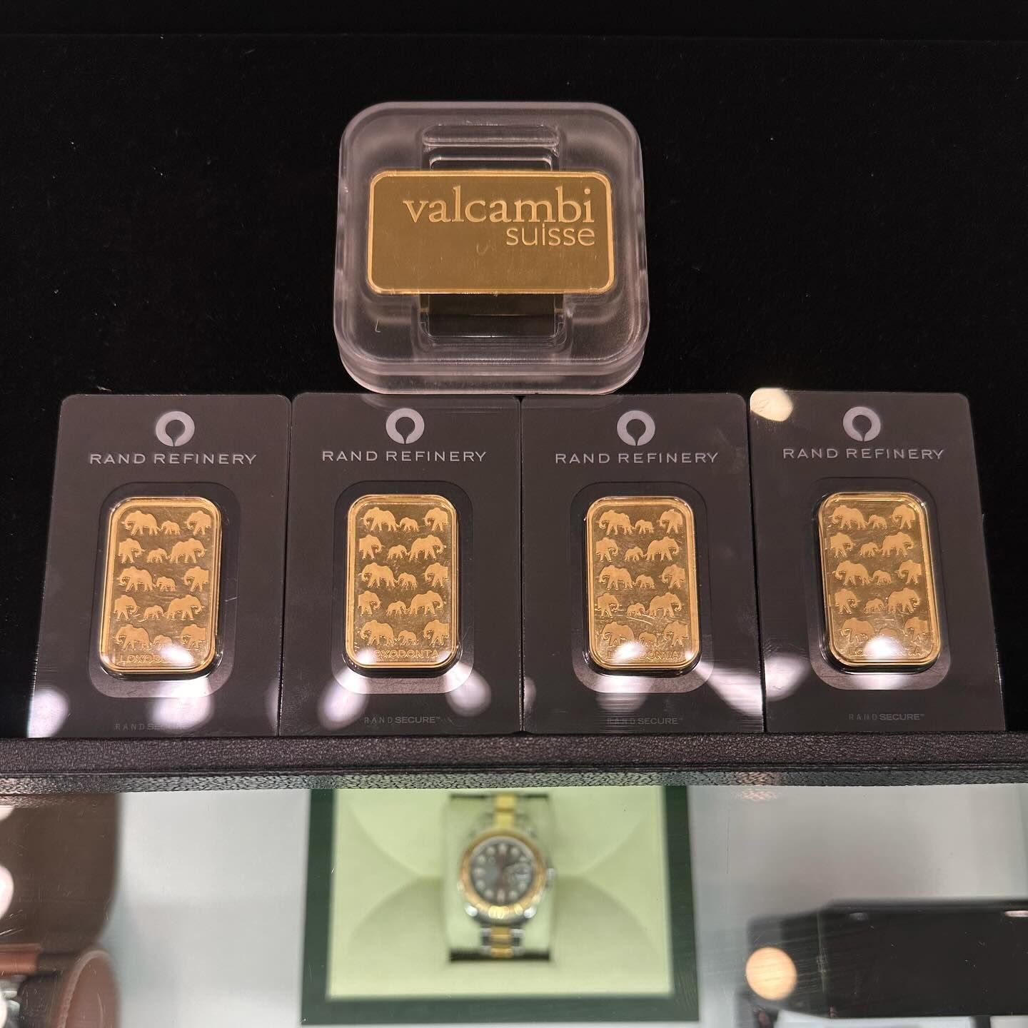 Valcambi Suisse gold bars displayed in a black case with a watch below