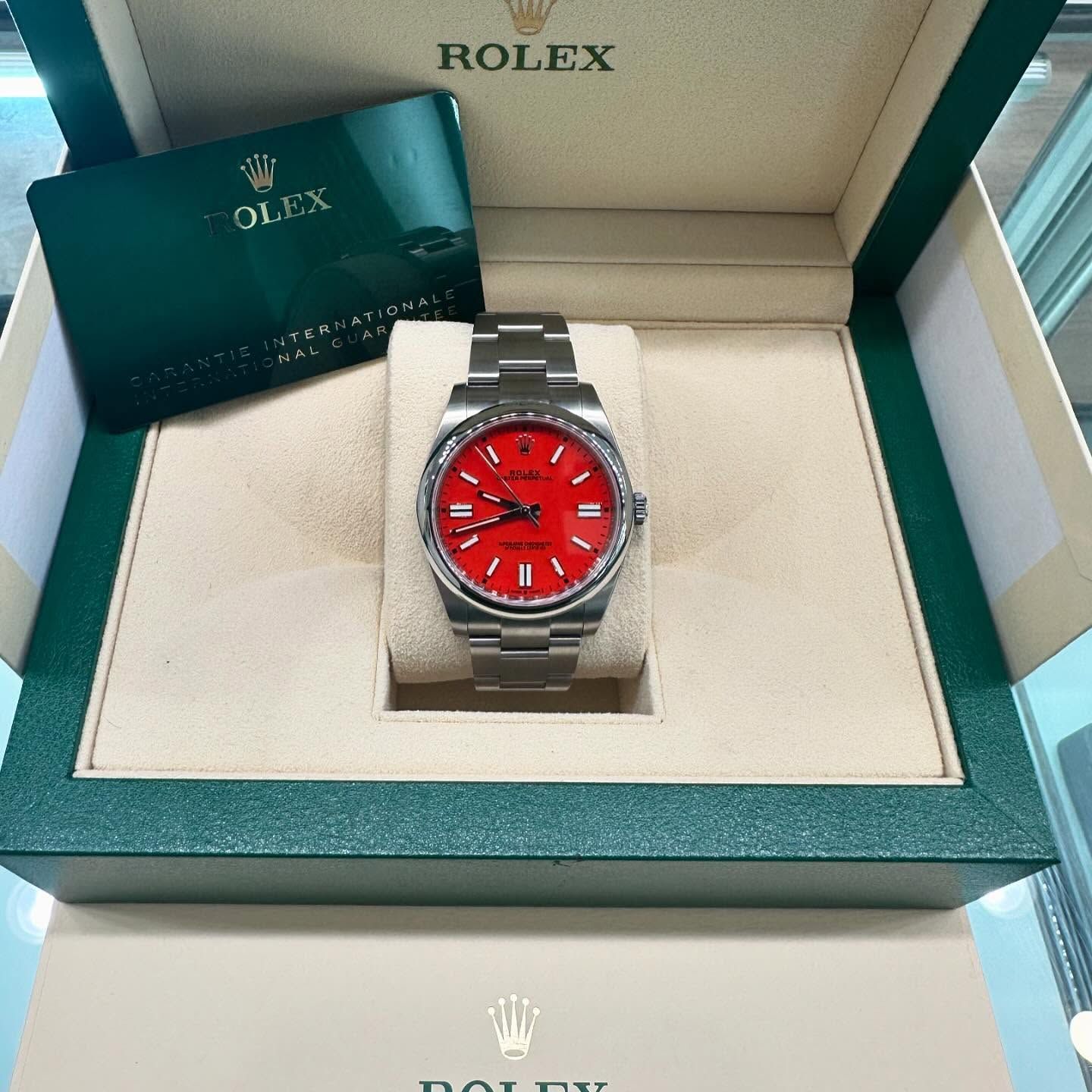 Rolex watch with red dial in an open green presentation box