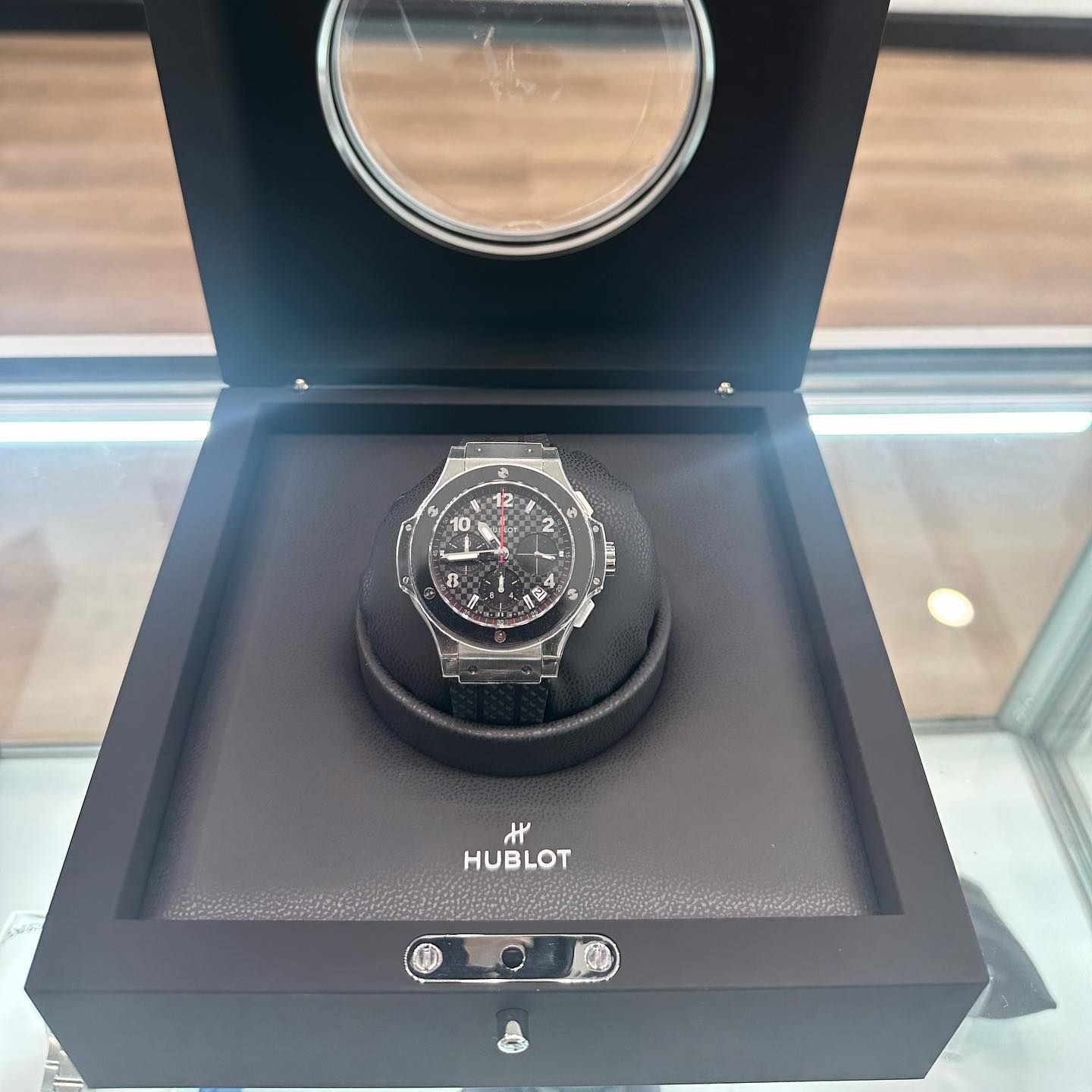 Hublot wristwatch displayed in a black luxury presentation box with a circular lid mirror.