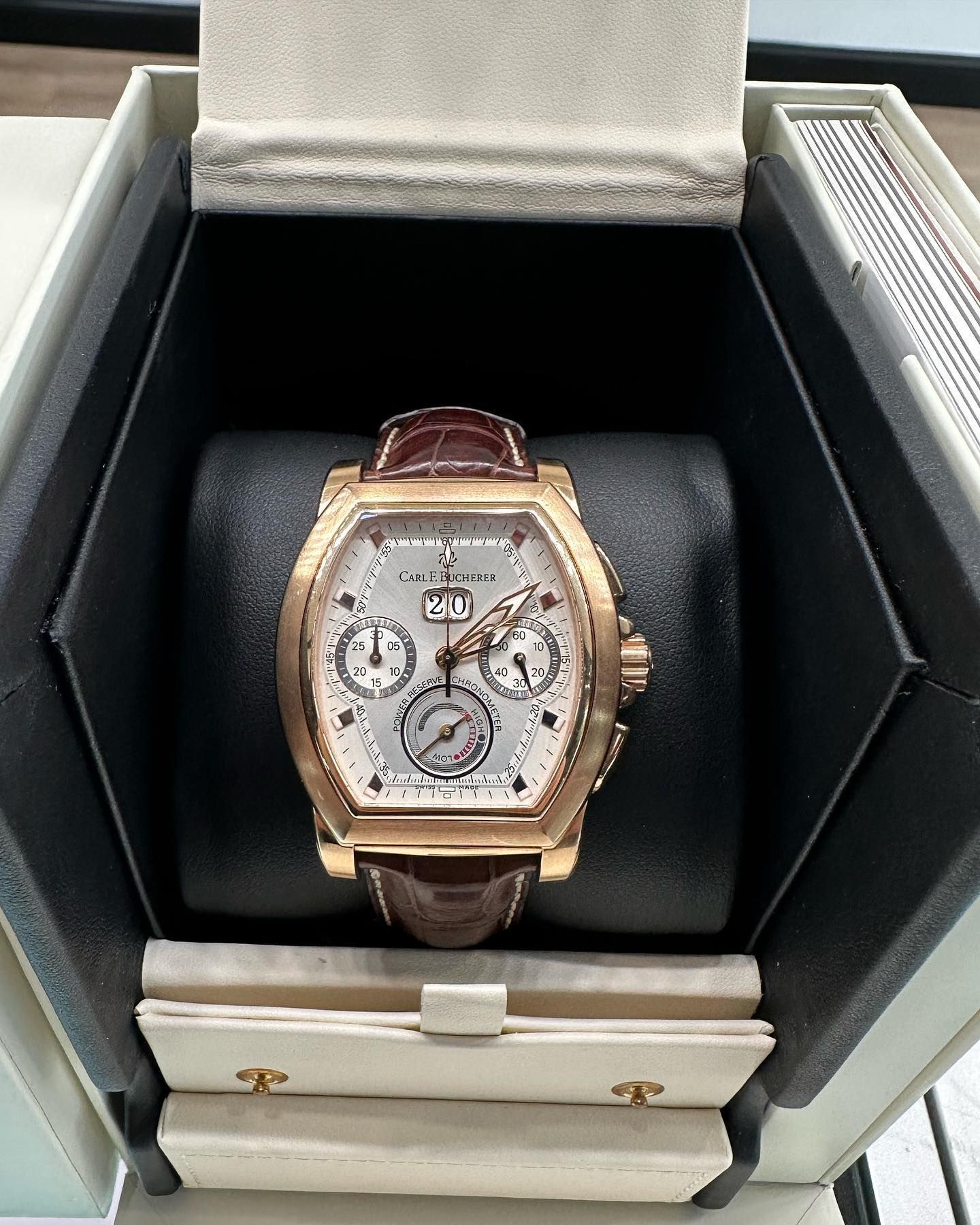 Gold watch with brown leather strap displayed in an open luxury box