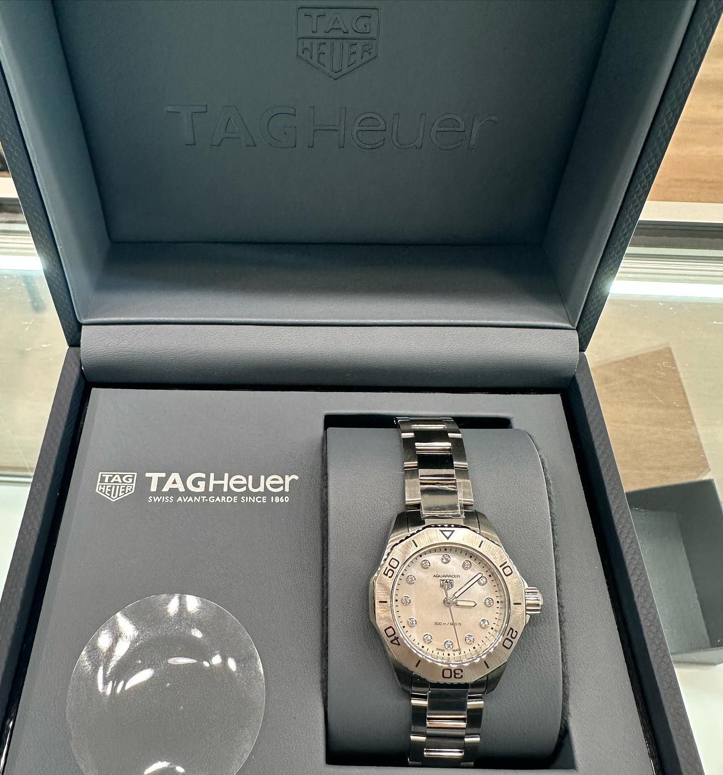 TAG Heuer watch in open presentation box, silver metal band with white dial and dark case interior