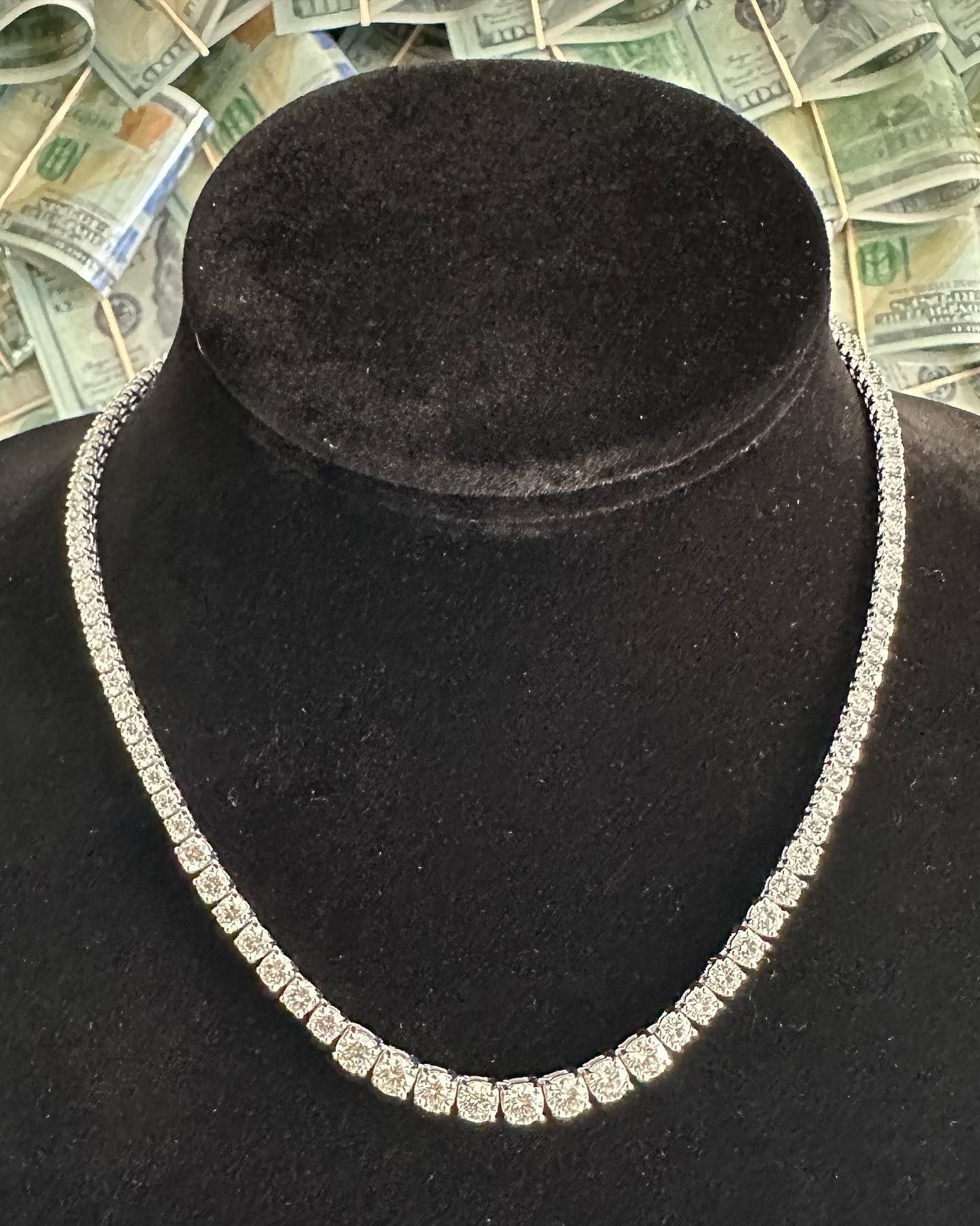 Diamond necklace on a black mannequin bust against a background of scattered currency.