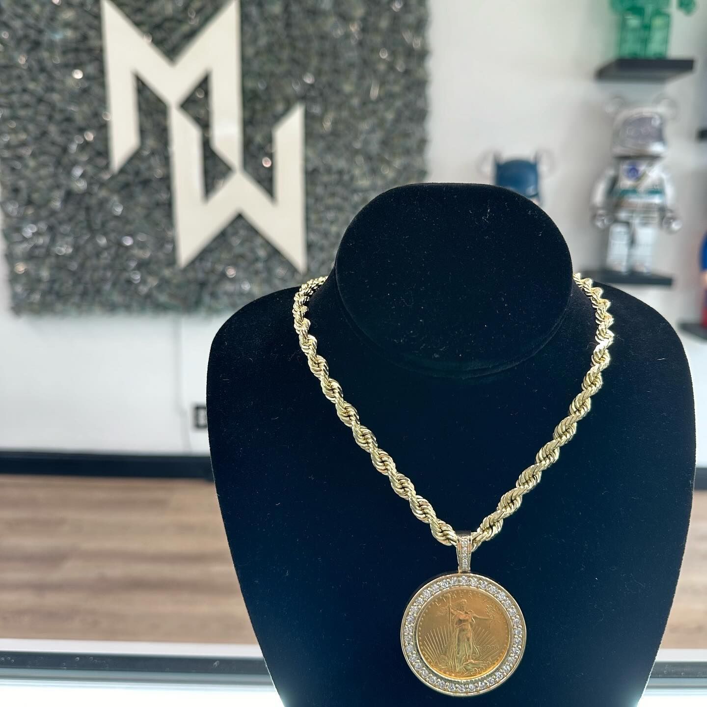 Gold pendant necklace on a black display bust in a jewelry showroom.