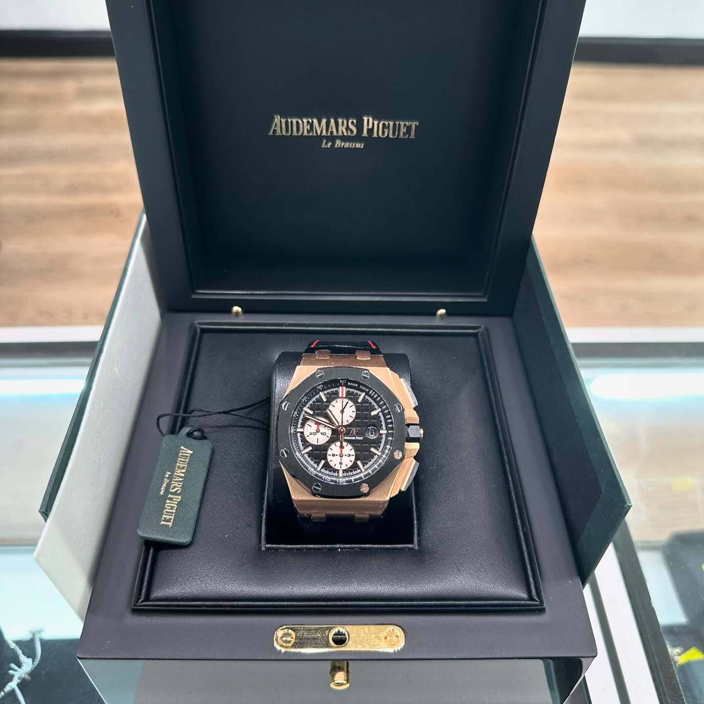 Audemars Piguet watch displayed in an open presentation box on a glass table.
