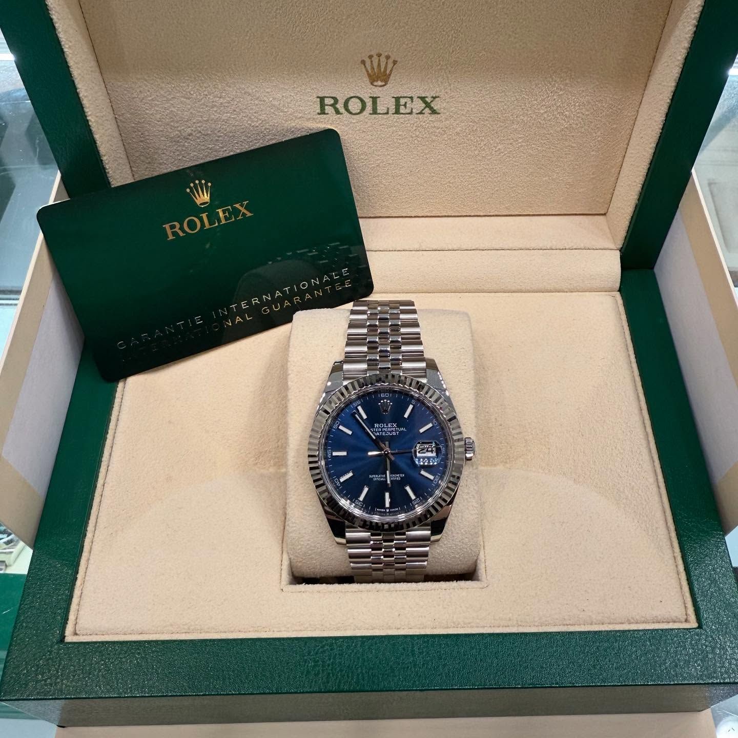 Rolex watch with blue face in an open green and cream presentation box