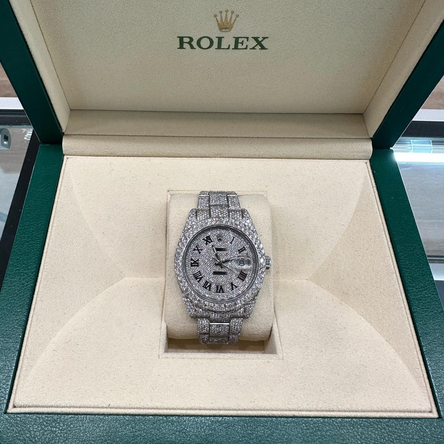 Diamond-encrusted Rolex watch displayed in an open green presentation box