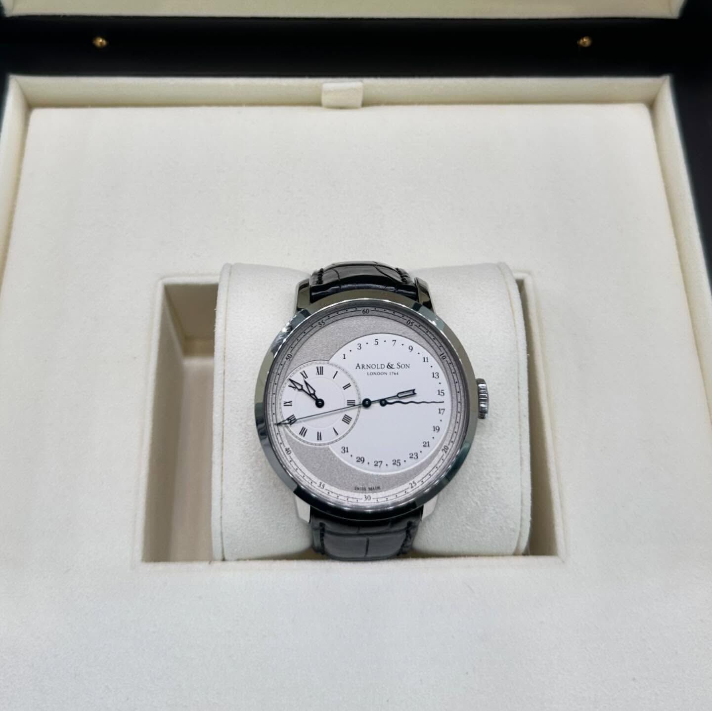 Silver wristwatch in a white presentation box with a white cushion