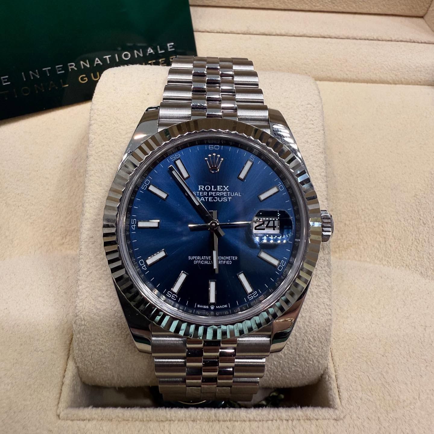 Blue-faced Rolex wristwatch with silver metal band in a beige display box
