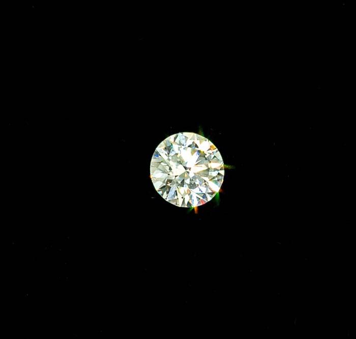 Round brilliant-cut diamond centered on a black background, sparkling with white highlights and tiny colored reflections