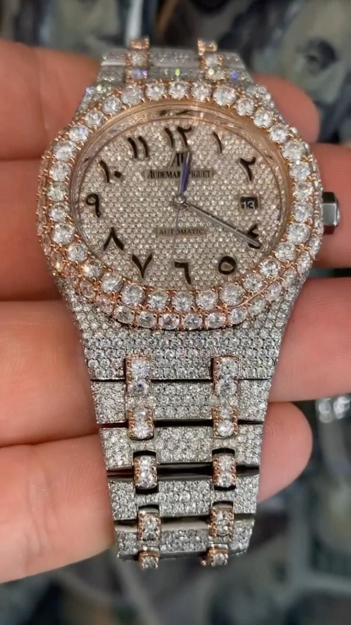 Diamond-encrusted wristwatch with silver band and gold-toned face on a hand