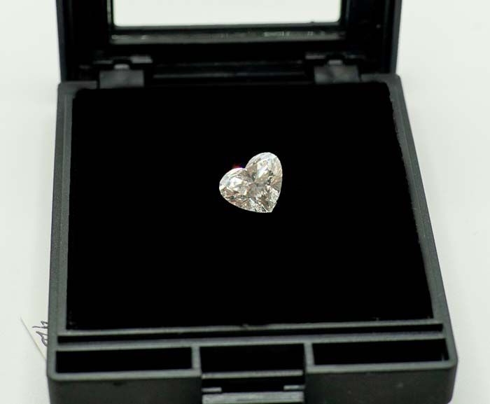Heart-shaped diamond in an open black jewelry box on a dark velvet lining