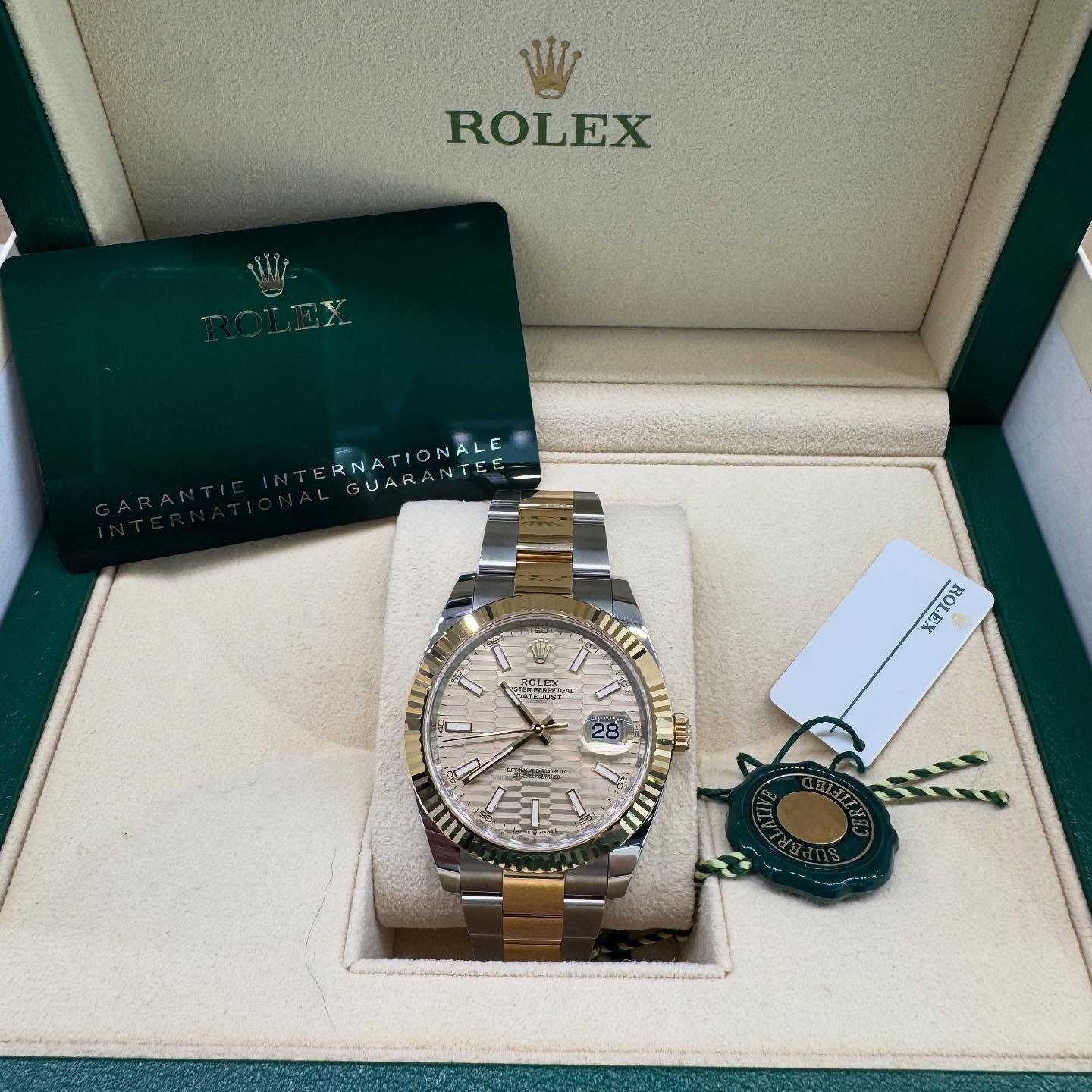 Rolex watch in a cream presentation box with green warranty card and tags
