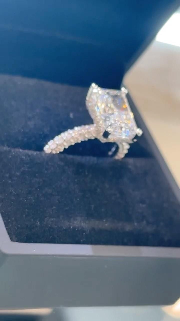 Diamond engagement ring in a navy velvet box, with a large square-cut center stone.
