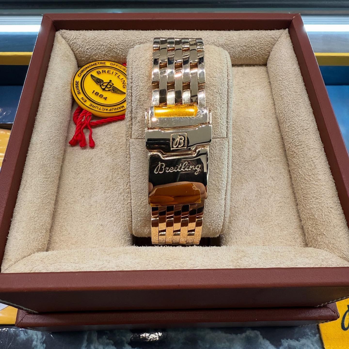 Silver wristwatch in a display box with a red-and-yellow tag on the left