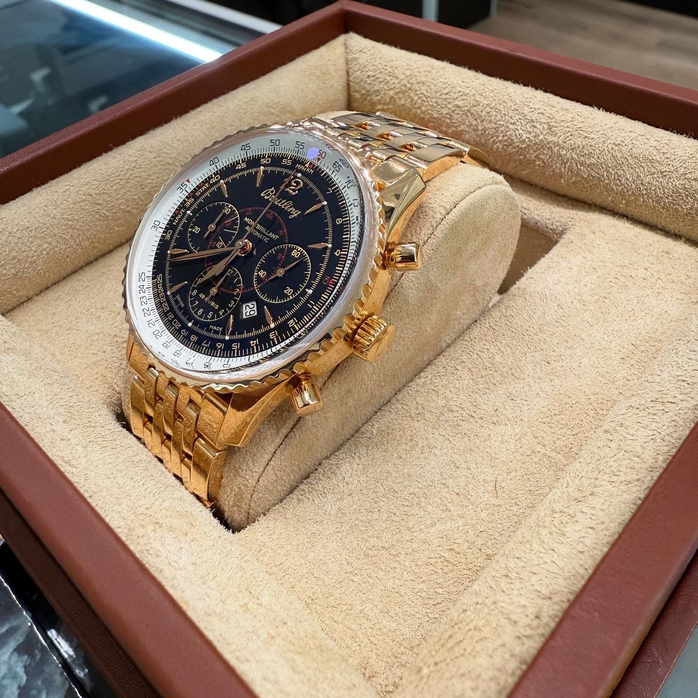 Gold-tone wristwatch with black dial displayed in a beige presentation box