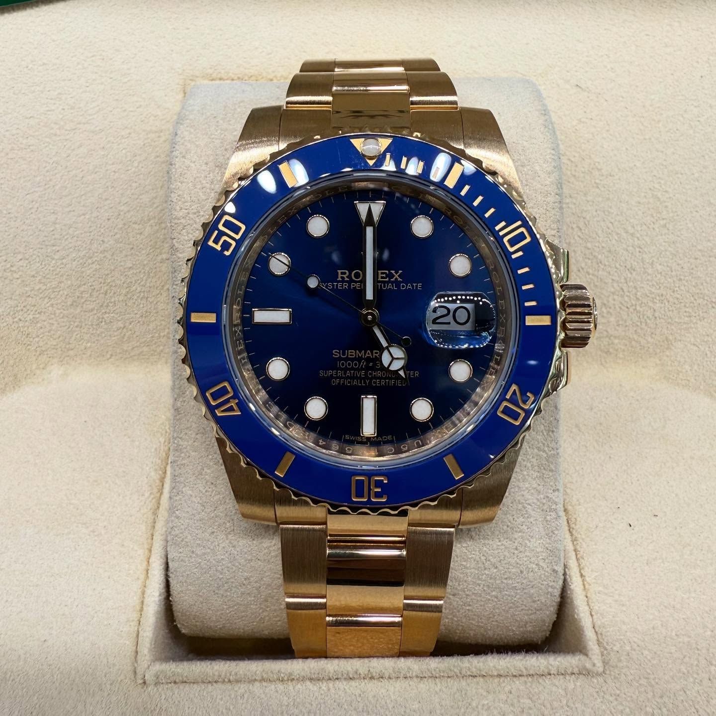 Gold Rolex watch with blue bezel and dial displayed on a cushion case