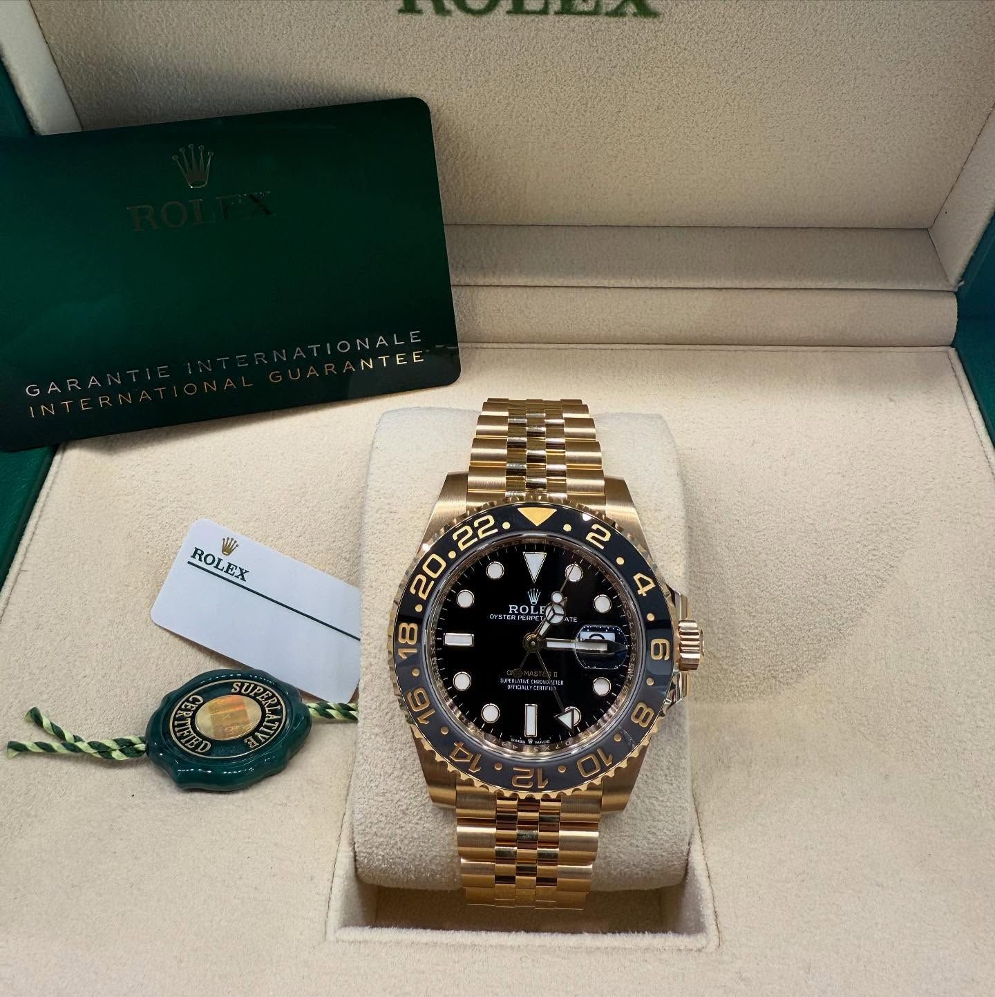 Gold Rolex watch in an open box with warranty card and green Rolex tag