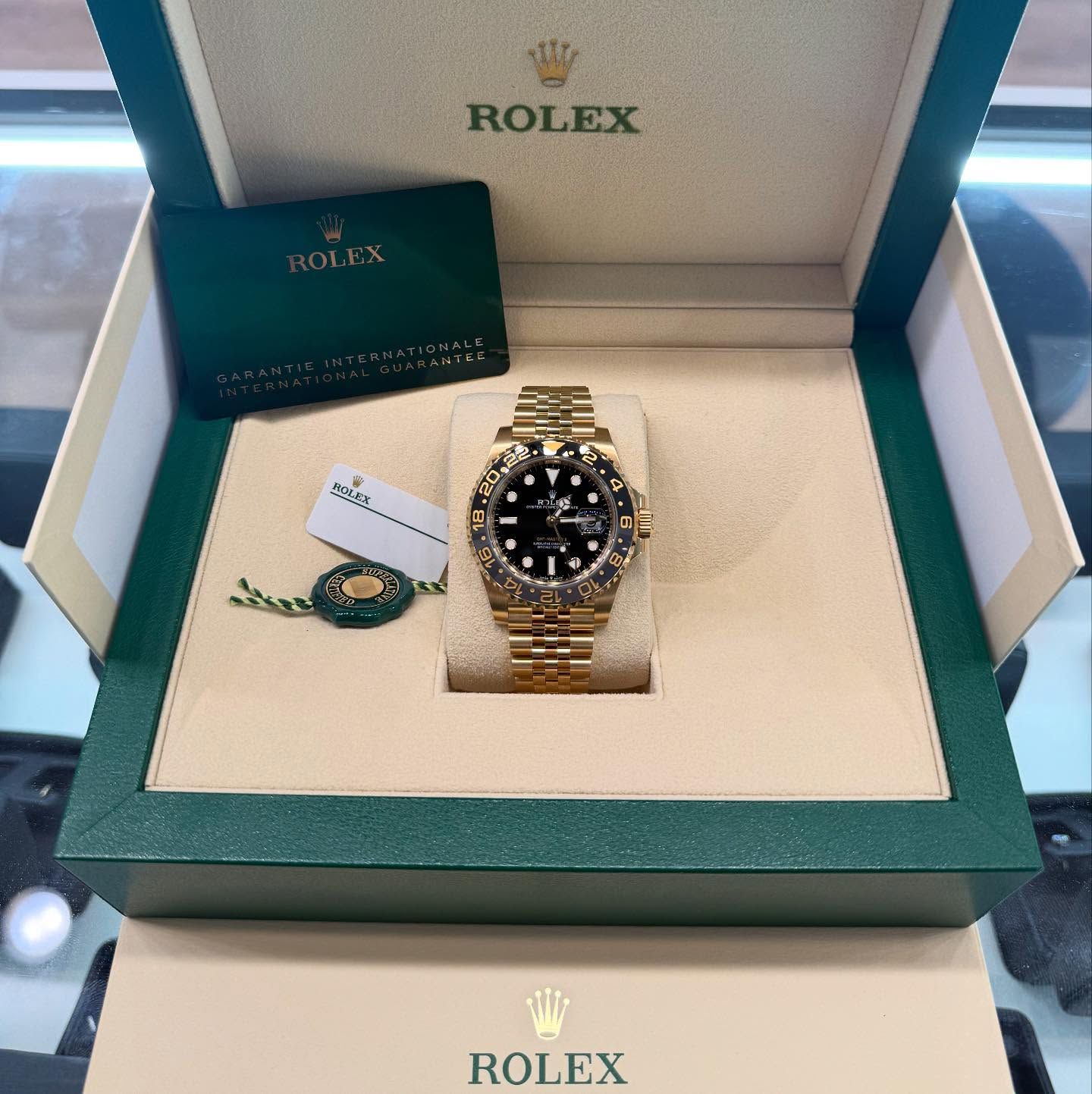 Rolex watch in open green-and-cream box with warranty card and tag