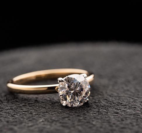 Gold ring with a large round diamond on a dark textured surface