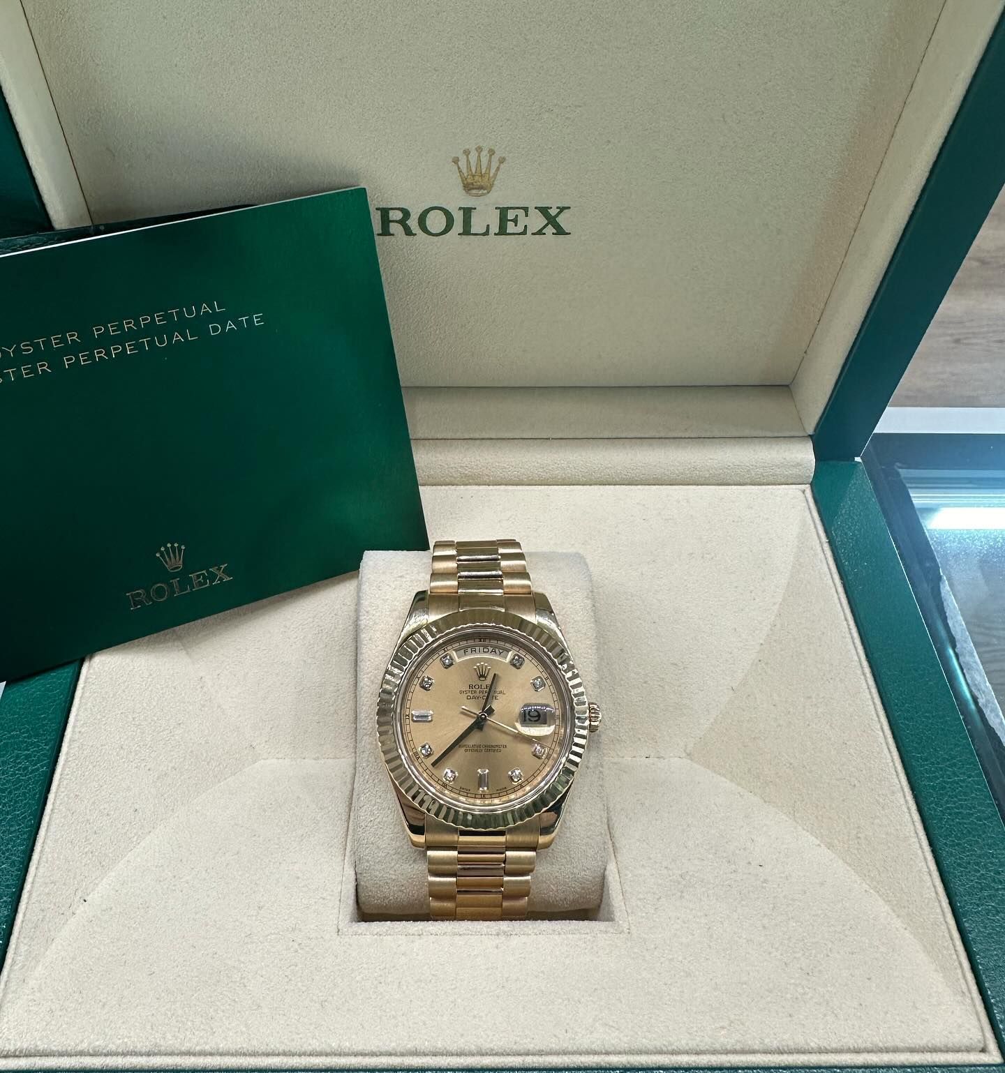 Rolex watch in an open green presentation box with a warranty booklet.