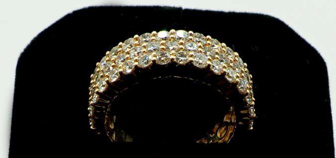 Gold and diamond ring on a black display stand, centered against a dark background