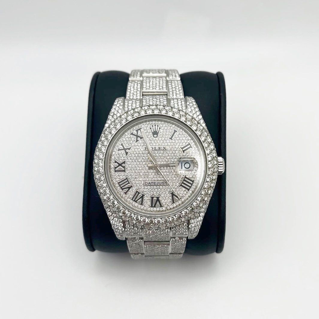 Diamond-encrusted silver wristwatch with Roman numerals on a black display cushion