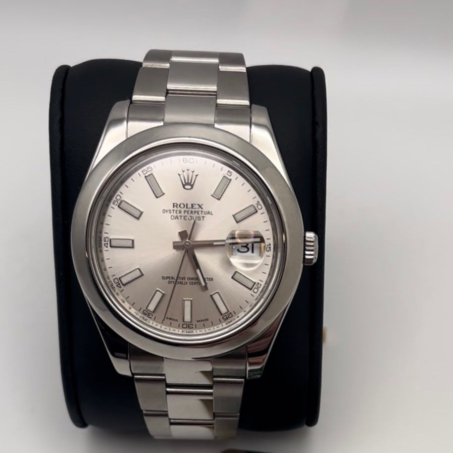 Silver Rolex wristwatch with a silver dial on a black display cushion