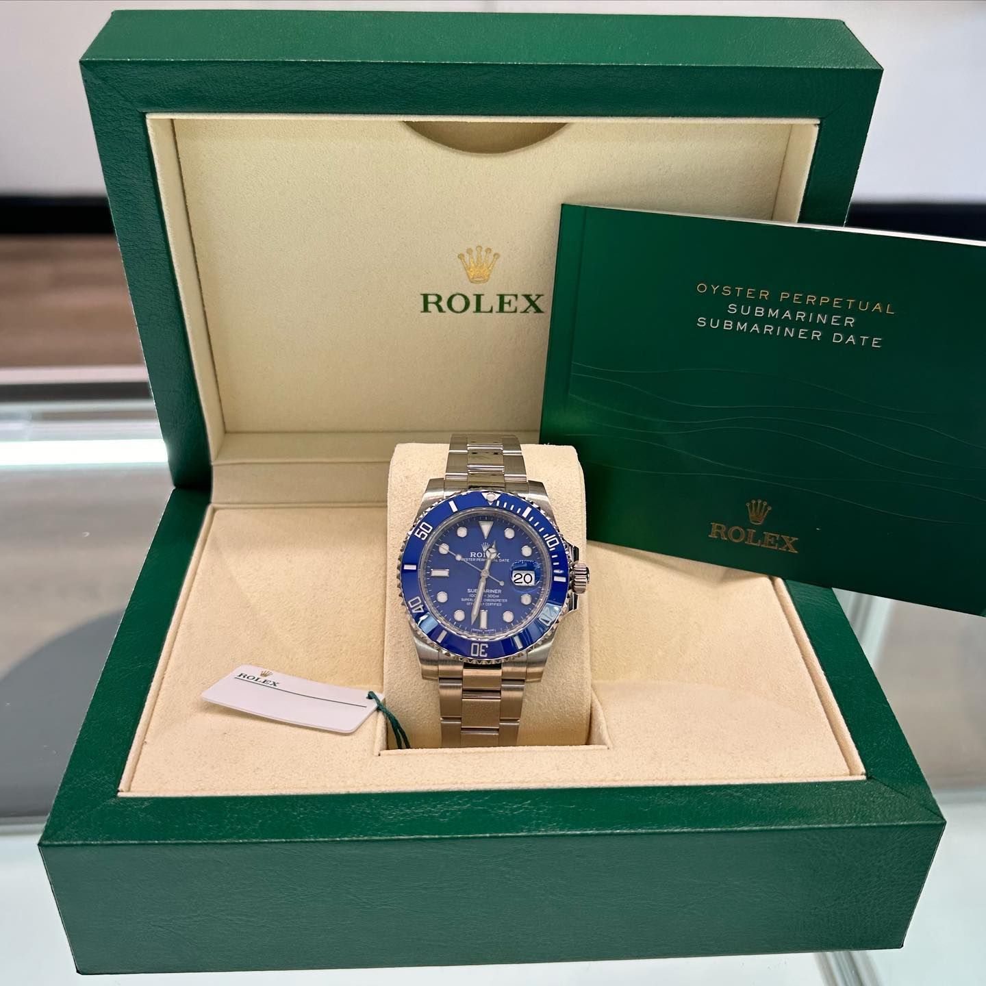 Blue Rolex watch in a green presentation box with papers and certificate booklet