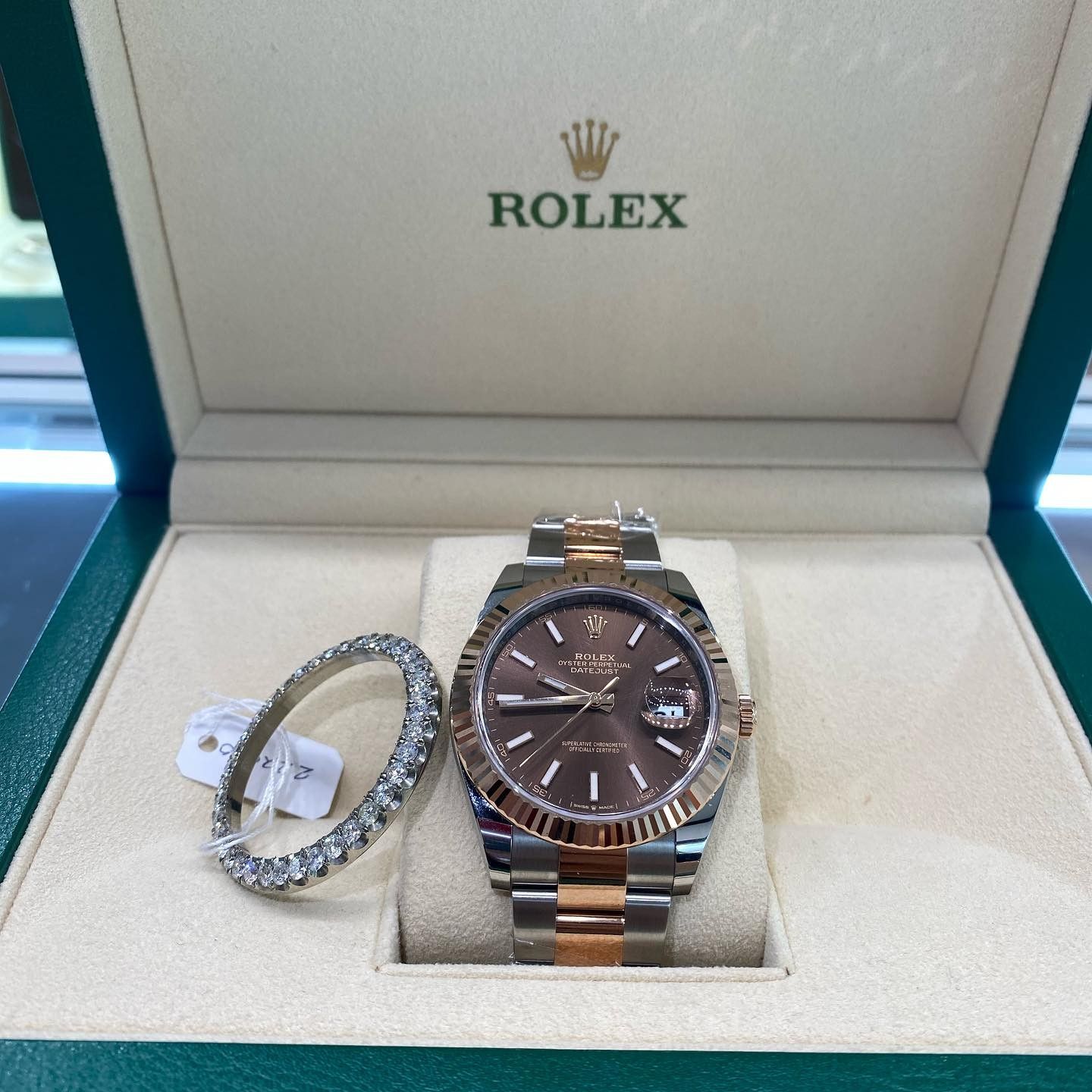 Rolex watch in an open green presentation box with a silver bracelet beside it
