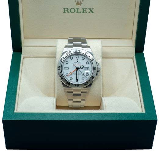 Rolex watch in an open green box with cream interior, displayed upright on a cushion