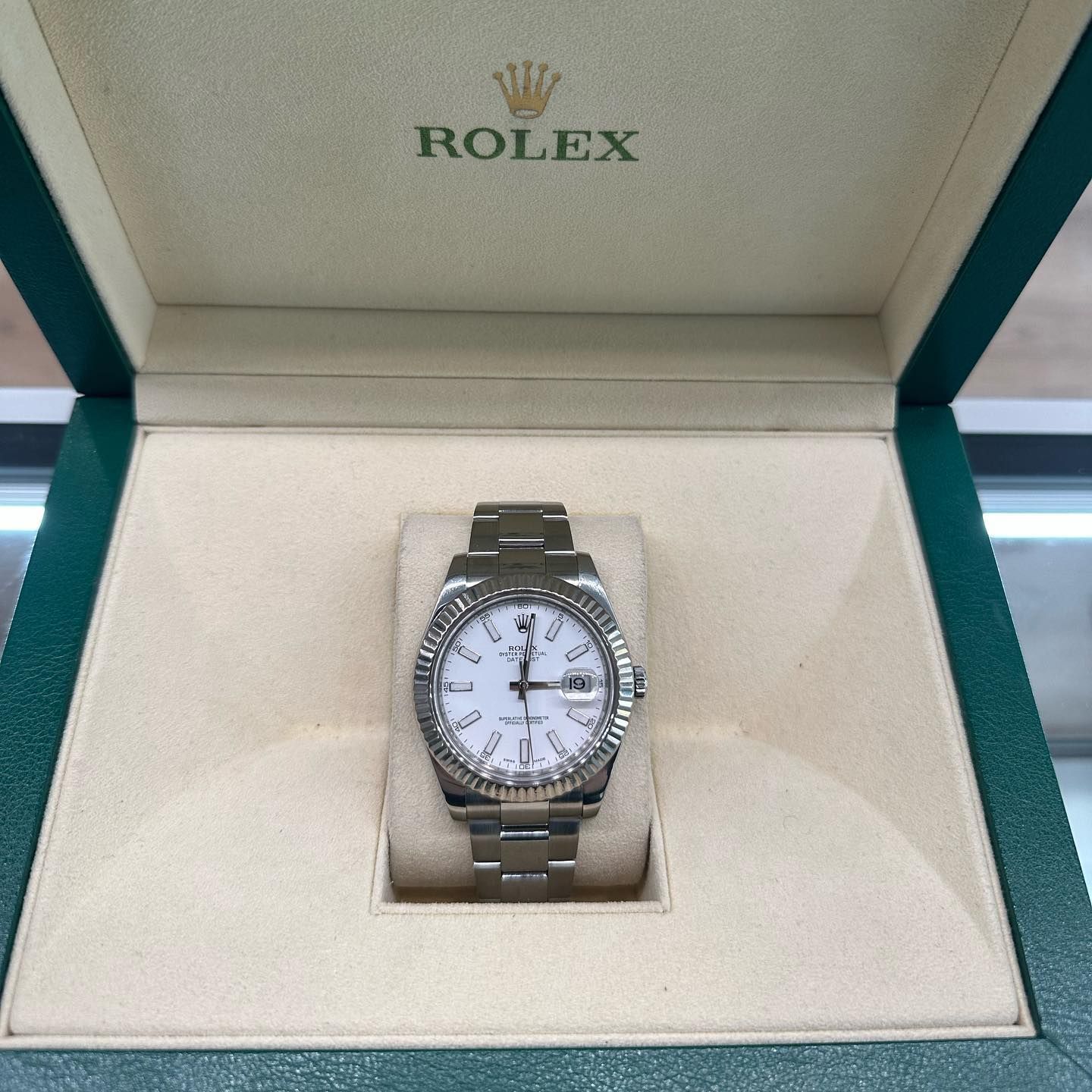 Rolex wristwatch in an open presentation box with a cream interior and green trim