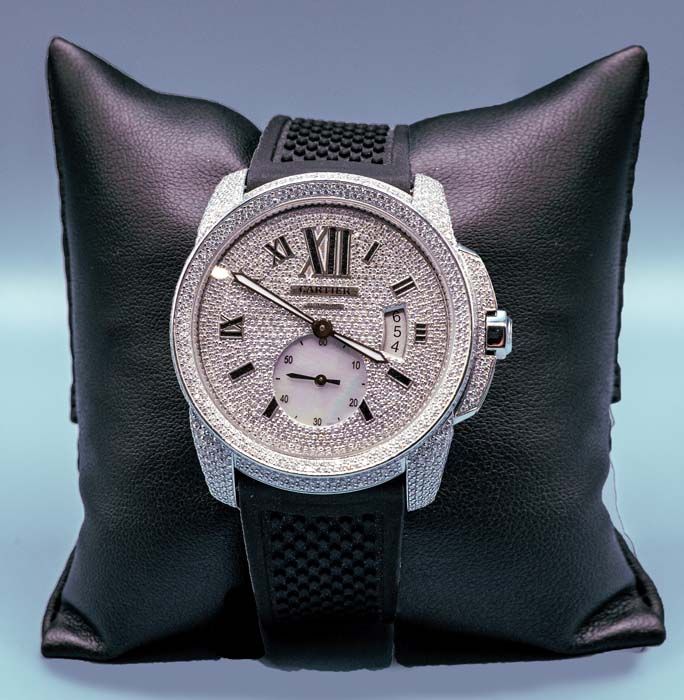 Silver watch with Roman numerals on a black cushion display stand