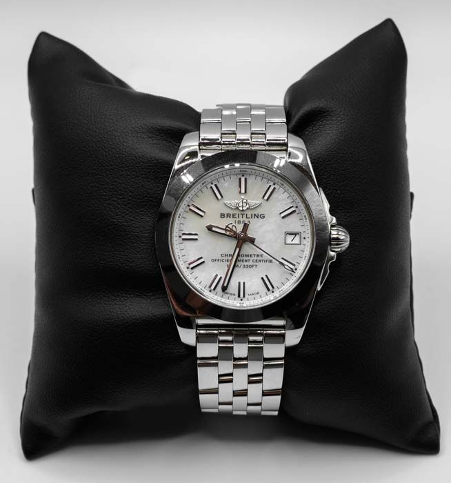 Silver wristwatch with white face on a black cushion, isolated background