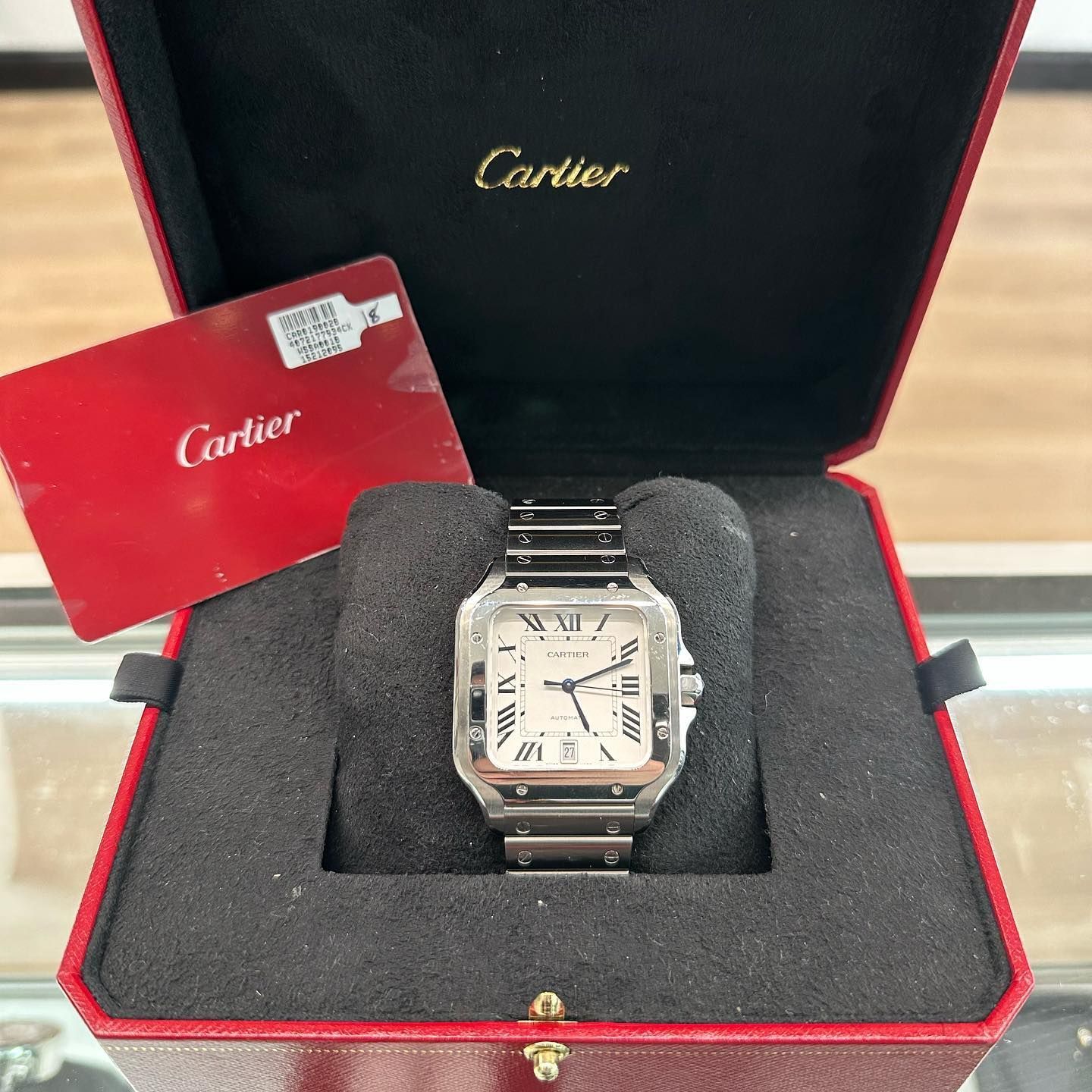 Cartier watch in a red presentation box with a warranty card beside it