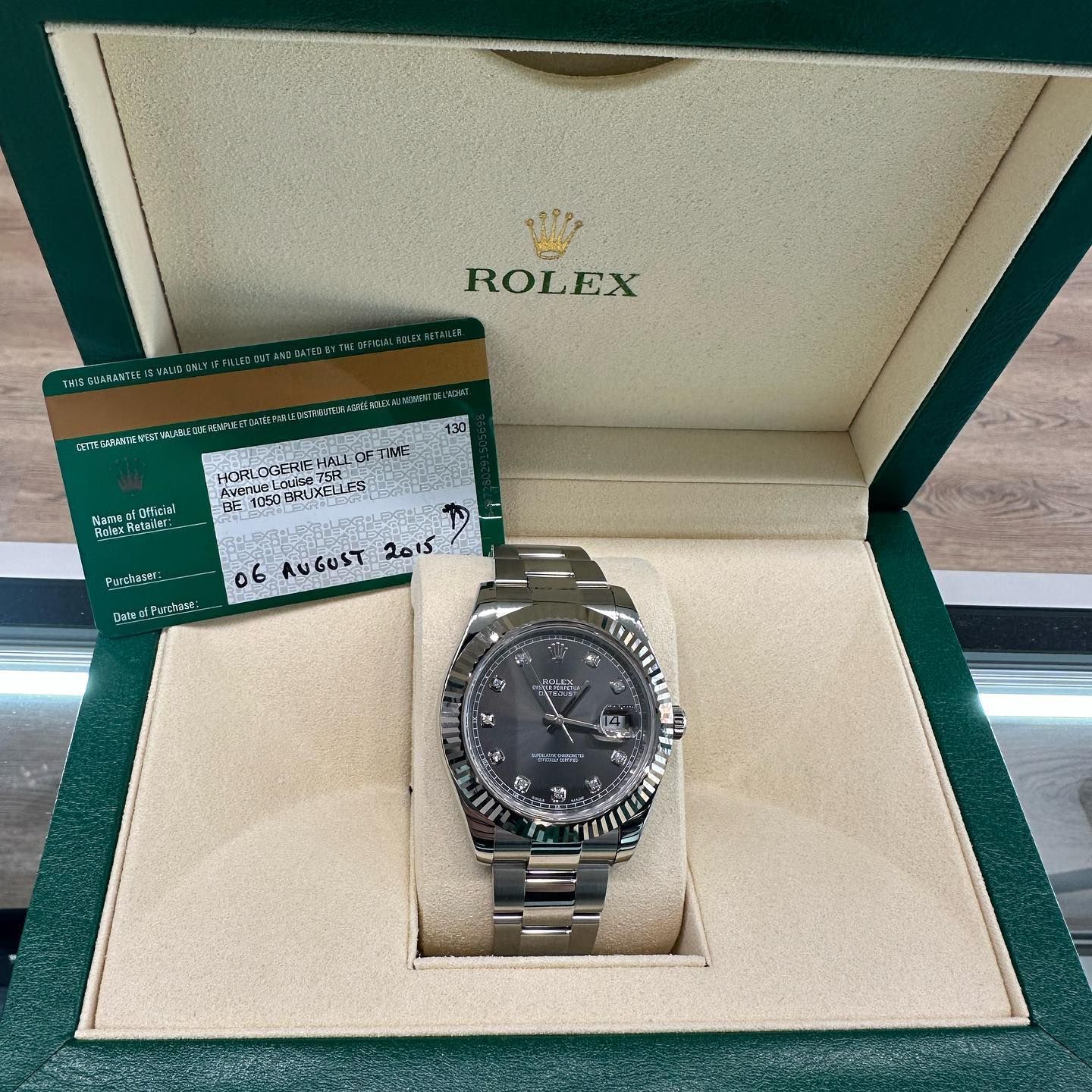 Rolex wristwatch in an open green presentation box with warranty card beside it