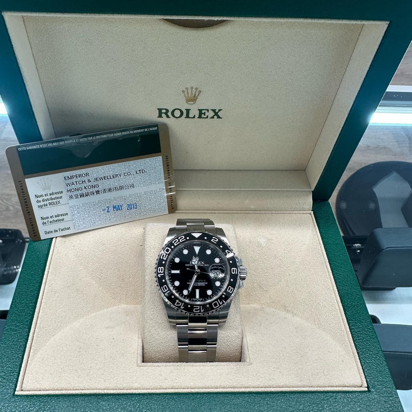 Rolex watch in an open presentation box with warranty card beside it