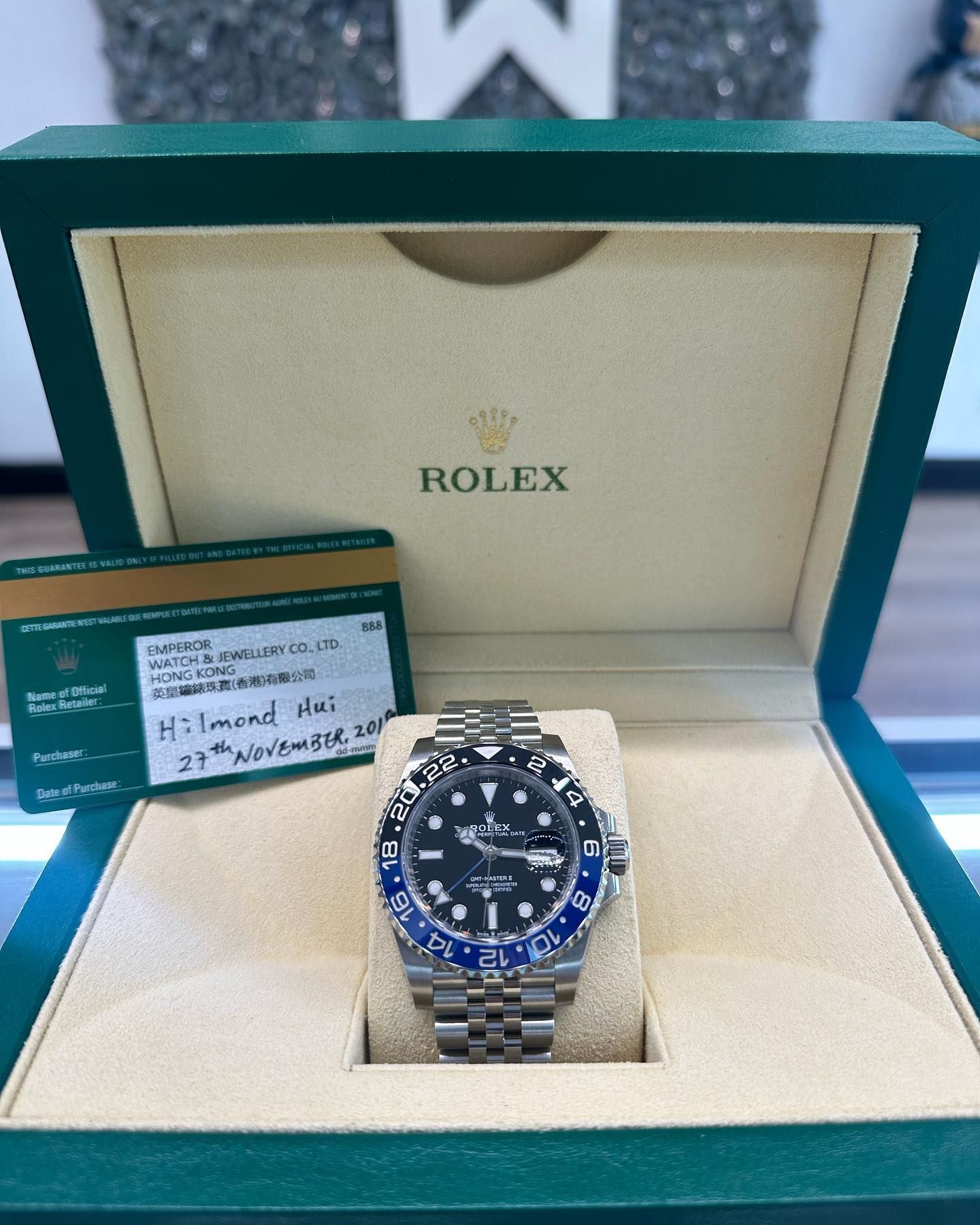 Rolex watch in green presentation box with warranty card beside it