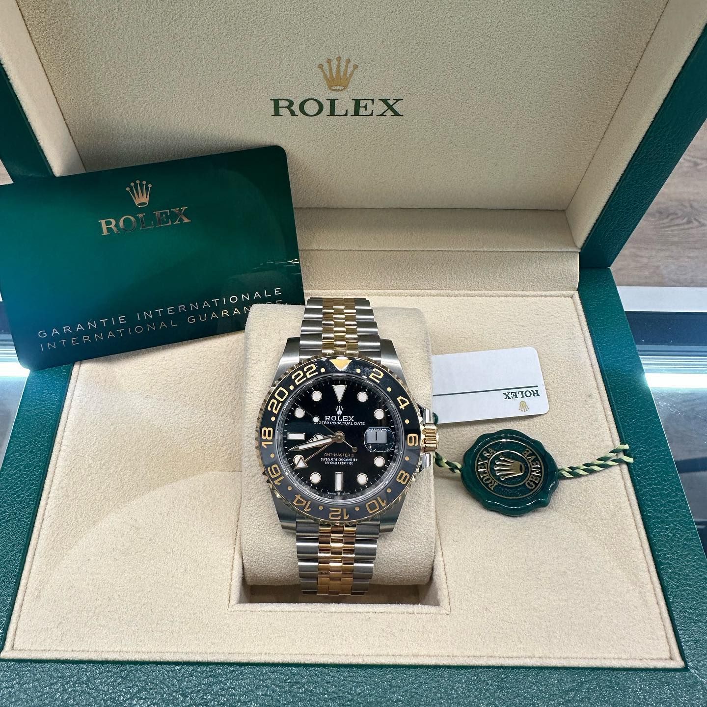 Rolex watch in a box with green card and tag, silver and gold bracelet, black dial