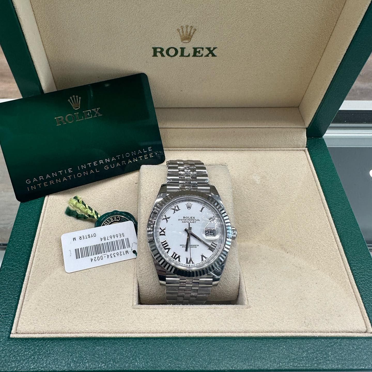 Rolex watch in green and beige presentation box with tag and certificate card