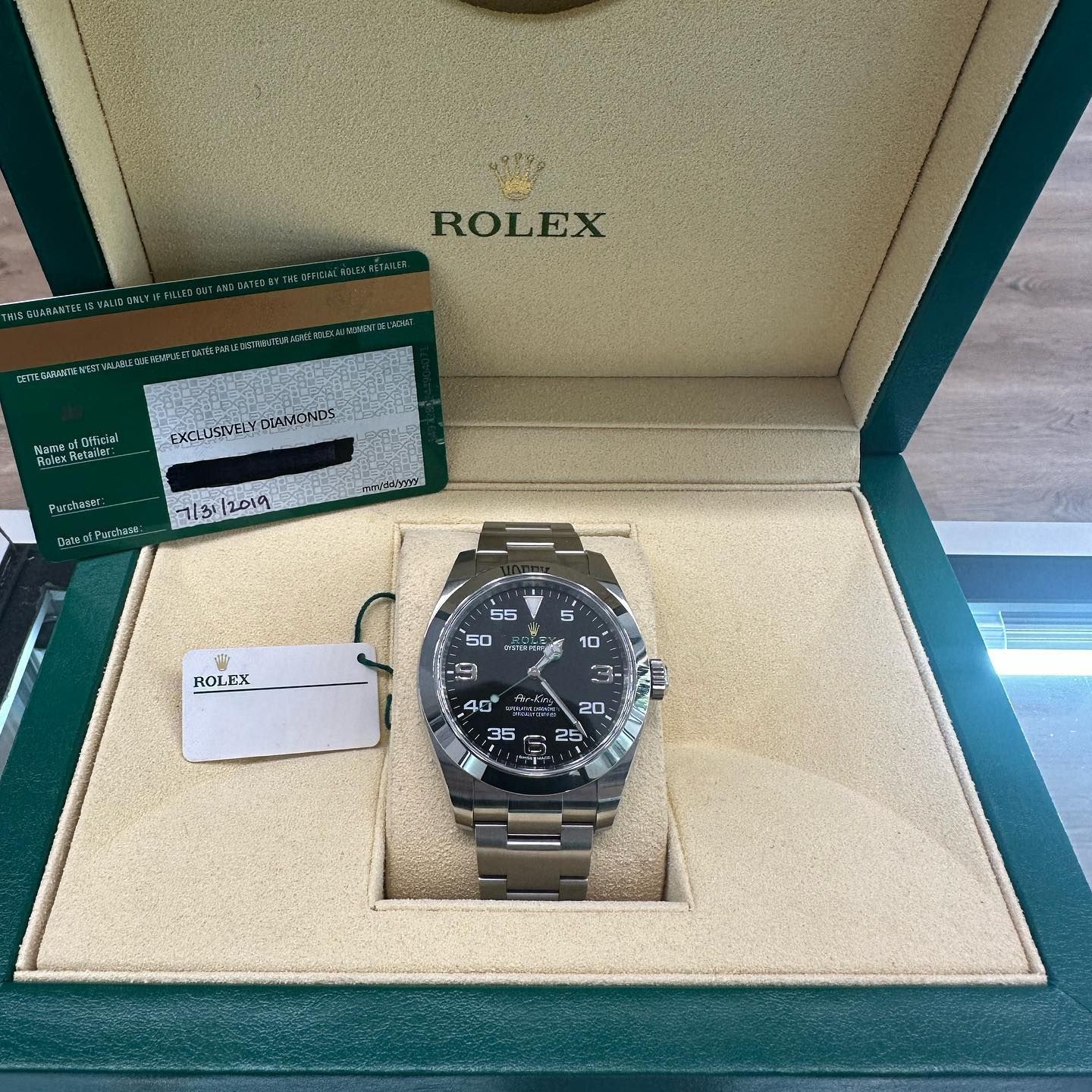 Rolex watch in an open green presentation box with warranty card and tag