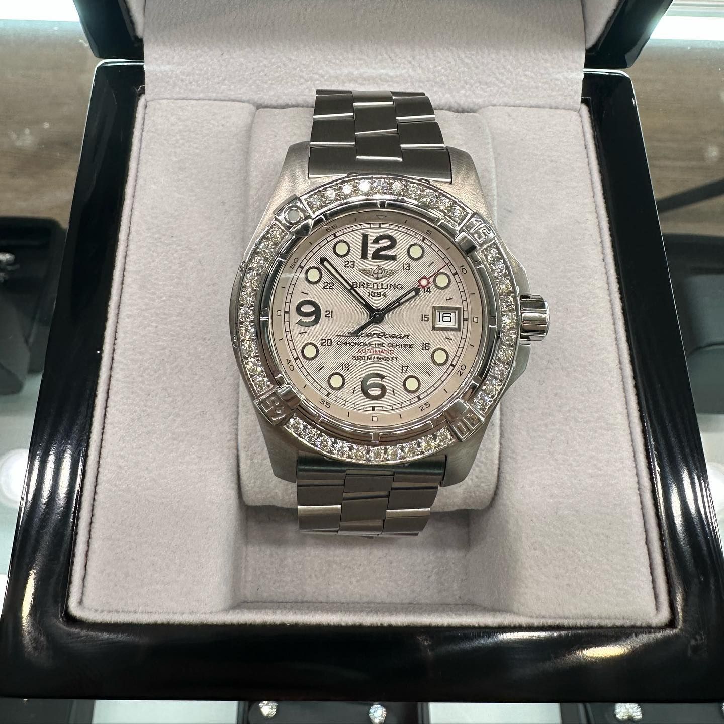 Silver diamond-studded wristwatch in a black presentation box