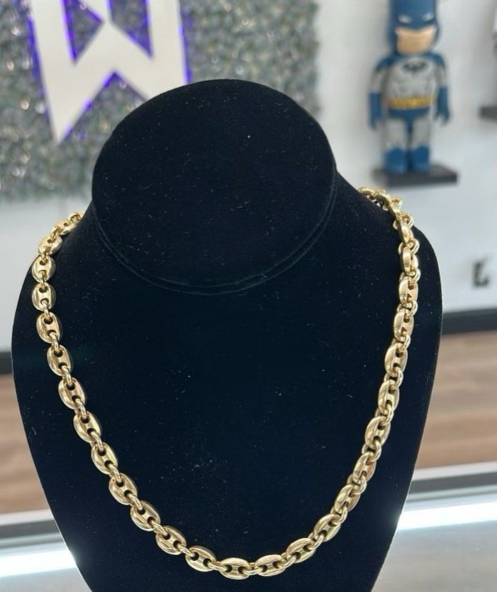 Gold chain necklace on a black velvet display bust.