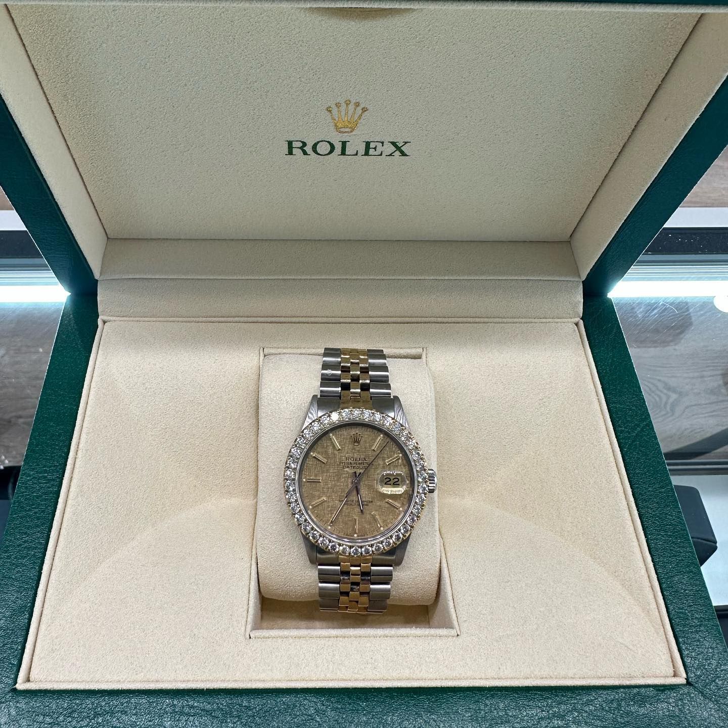 Rolex wristwatch with a gold dial and diamond bezel displayed in an open presentation box.