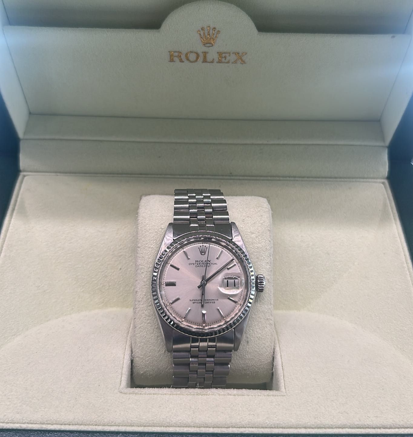 Rolex wristwatch with pink face displayed in an open Rolex presentation box.